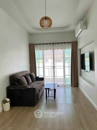 Modern living room with stylish sofa, wall-mounted TV, and large window for natural light.
