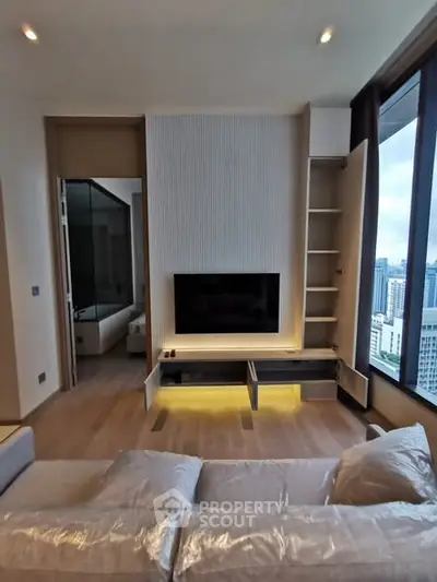 Modern living room with city view, featuring sleek TV setup and cozy seating area.