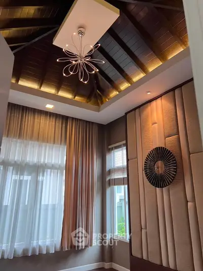 Elegant living room with high ceiling and modern chandelier, featuring large windows and stylish wall decor.