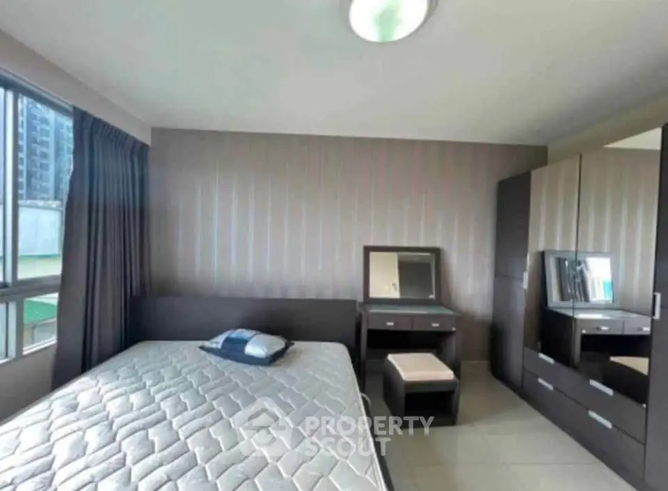 Modern bedroom with sleek furniture and large window offering natural light.