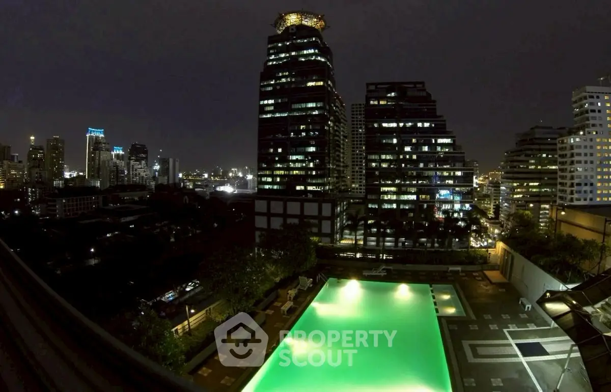 Stunning night view of city skyline with illuminated rooftop pool in luxury building.