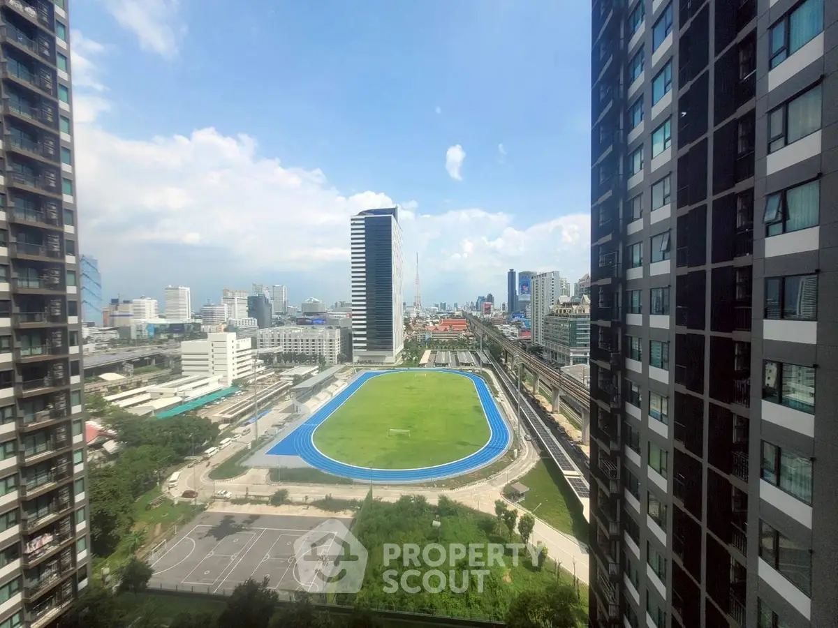 Stunning cityscape view from high-rise building with sports field and urban skyline.
