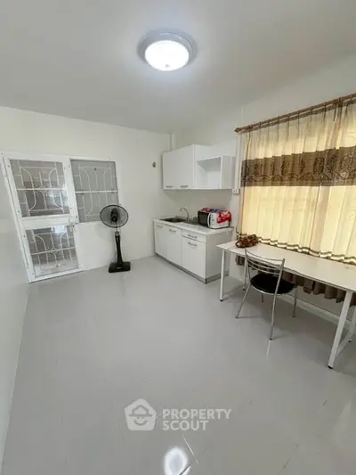 Bright minimalist kitchen with white cabinets and dining area