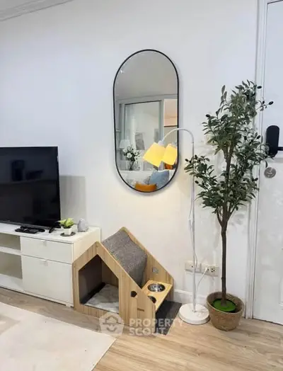 Chic living room with modern decor, TV unit, pet house, and stylish mirror.