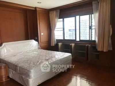 Spacious bedroom with large windows and wooden flooring in a modern apartment.