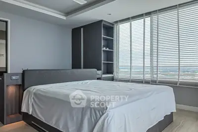 Modern bedroom with large windows and sleek design in a high-rise apartment.