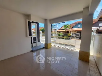 Spacious covered patio with tiled flooring and street view, perfect for outdoor relaxation.