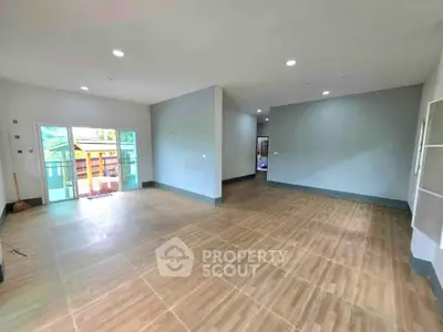 Spacious open-plan living room with large windows and wooden flooring