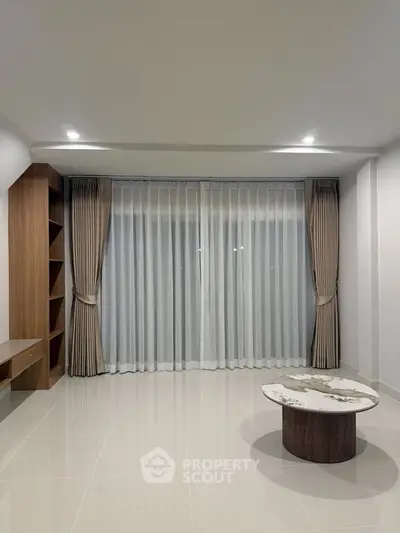 Spacious living room with elegant curtains and modern decor, perfect for relaxation and entertainment.