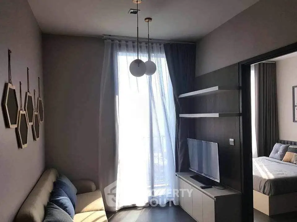Modern living room with natural light, stylish decor, and a glimpse into a cozy bedroom.
