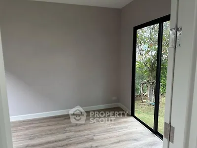 Spacious empty room with large window and garden view, perfect for customization.