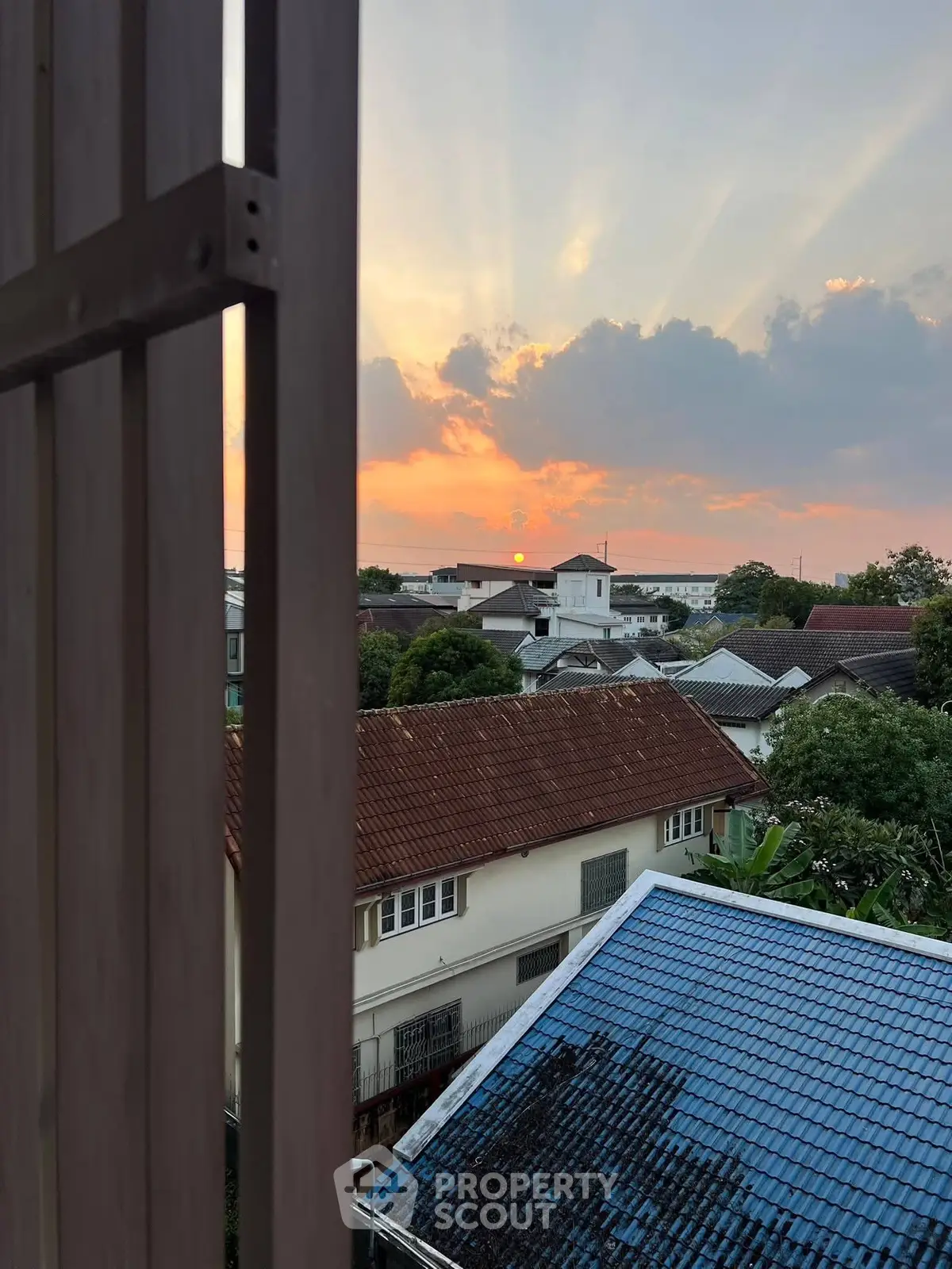 Charming sunset view over suburban rooftops with vibrant sky colors.