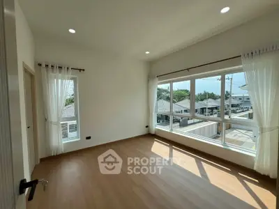 Bright and spacious bedroom with large windows and wooden flooring in modern home.