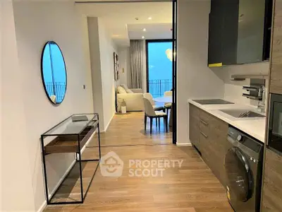 Modern apartment interior with open kitchen and living area, featuring sleek design and wooden flooring.