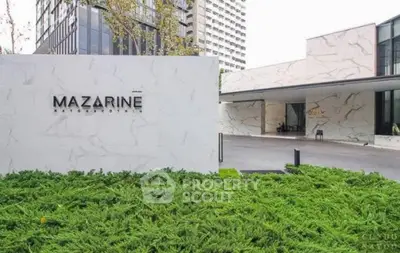 Luxurious modern building entrance with sleek marble facade and lush greenery.