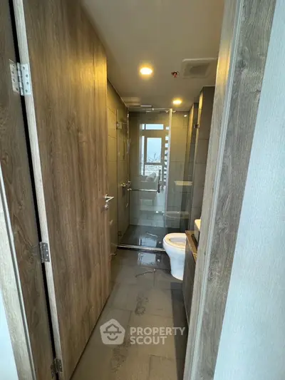 Modern bathroom with wooden accents and glass shower enclosure