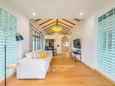 Spacious living room with modern decor and open layout, featuring a cozy sofa and elegant lighting.