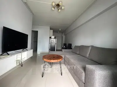Modern living room with sleek gray sofa, stylish coffee table, and flat-screen TV in a contemporary apartment.