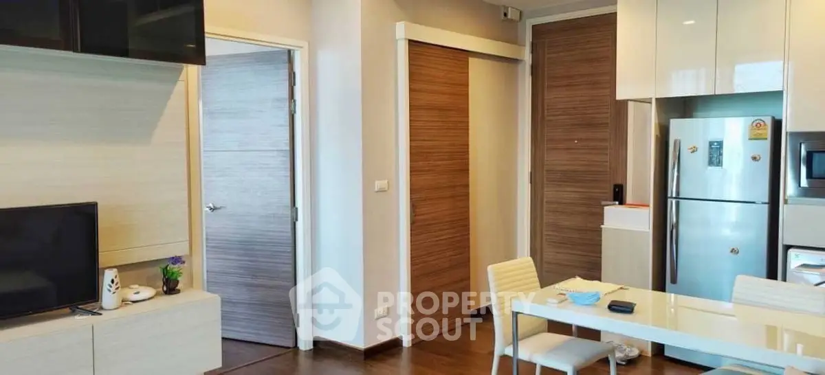 Modern apartment interior with sleek kitchen and dining area, featuring contemporary furniture and appliances.