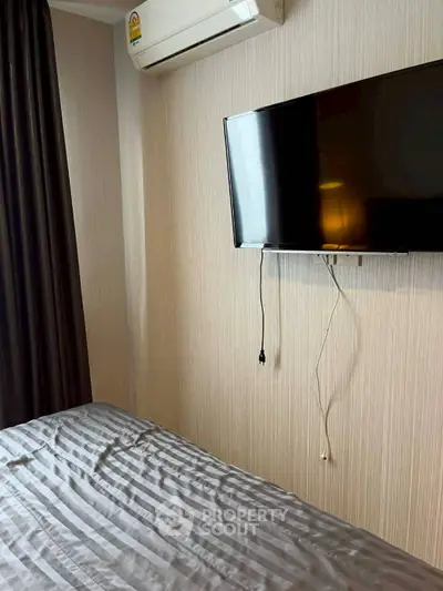 Cozy bedroom with wall-mounted TV and air conditioning, perfect for modern living.
