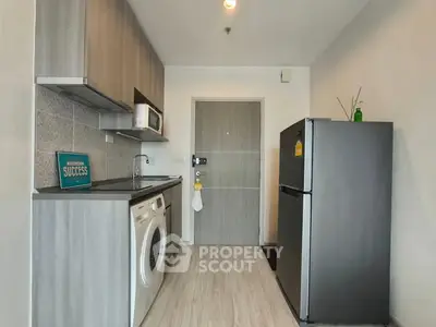Modern kitchen with washing machine, fridge, and sleek cabinetry in compact layout.