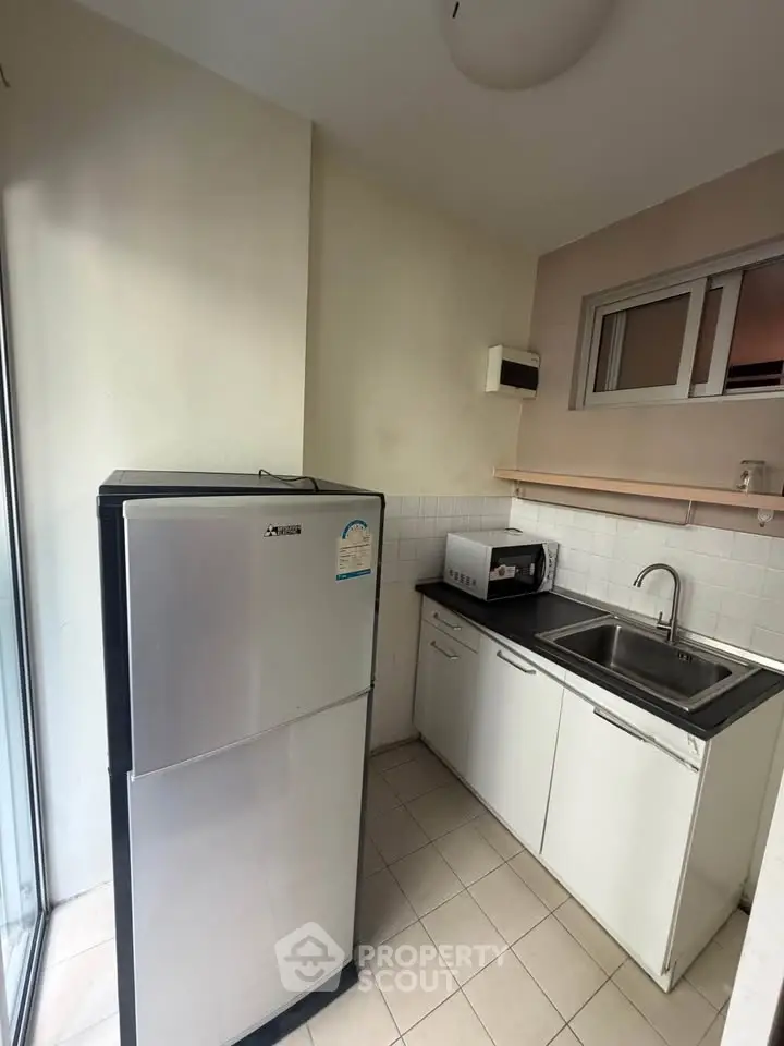 Compact kitchen with modern fridge and sink in cozy apartment