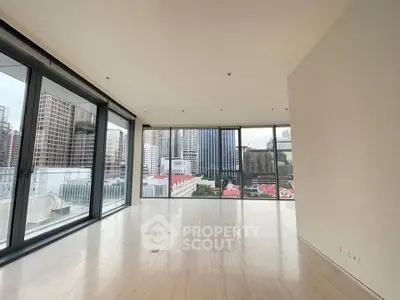 Spacious modern living room with floor-to-ceiling windows and stunning city view.