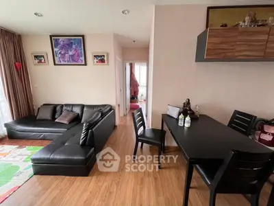 Modern living room with black leather sofa and dining area, featuring wooden flooring and stylish decor.