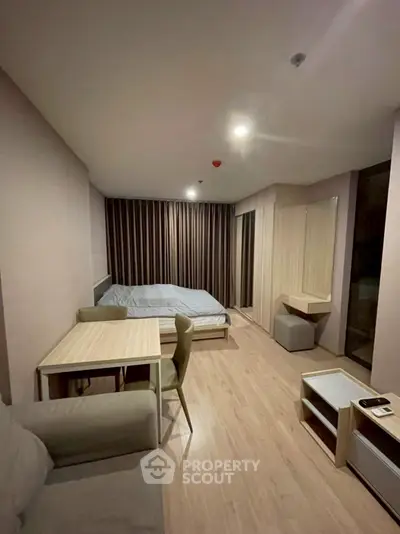 Modern studio apartment with cozy bedroom and dining area, featuring stylish furniture and warm lighting.