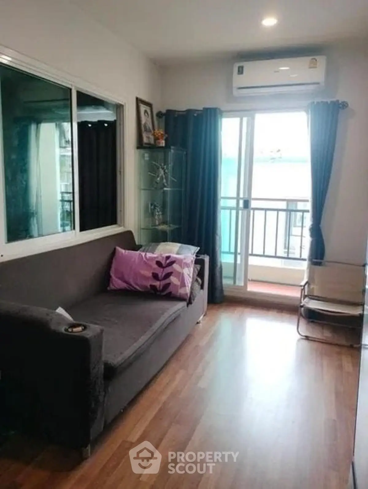 Cozy living room with modern sofa and balcony access, perfect for relaxation and natural light.