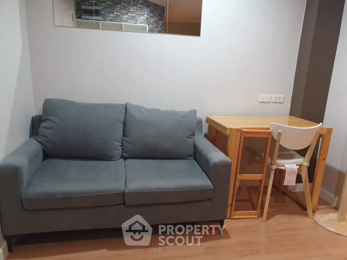 Cozy living room with modern gray sofa and wooden desk, perfect for small spaces.