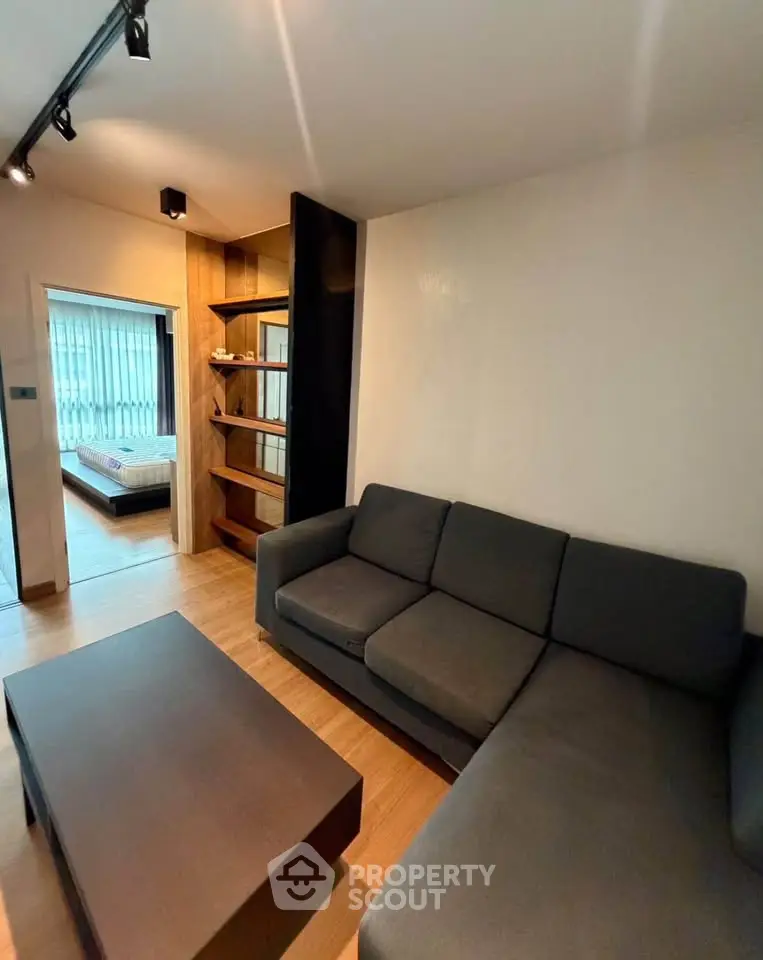 Modern living room with sleek furniture and open view to bedroom
