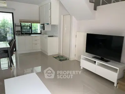 Modern open-plan living room with sleek kitchen and large TV