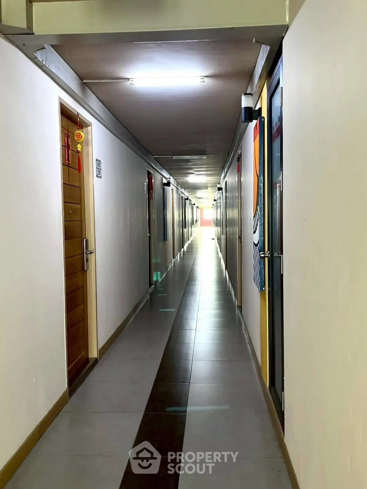 Long corridor in residential building with modern lighting and tiled flooring.