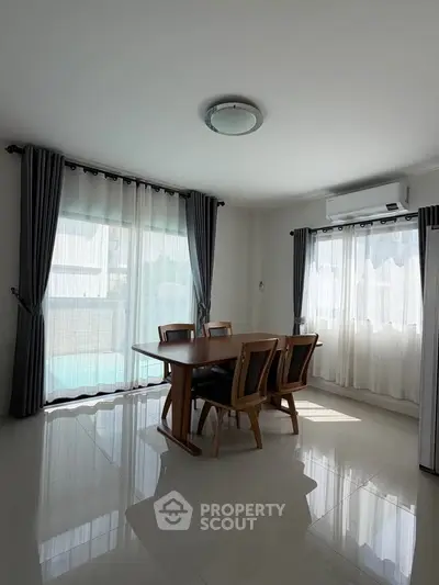 Bright dining area with large windows and modern furniture in a spacious home.
