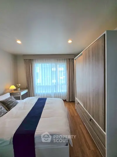 Cozy bedroom with modern decor and large window offering natural light.