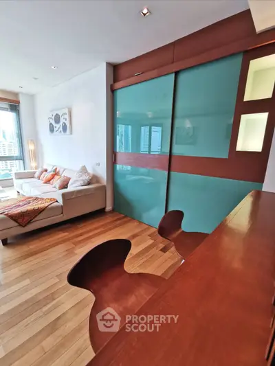 Stylish modern living room with wooden flooring and sliding glass doors, featuring elegant furniture and contemporary decor.