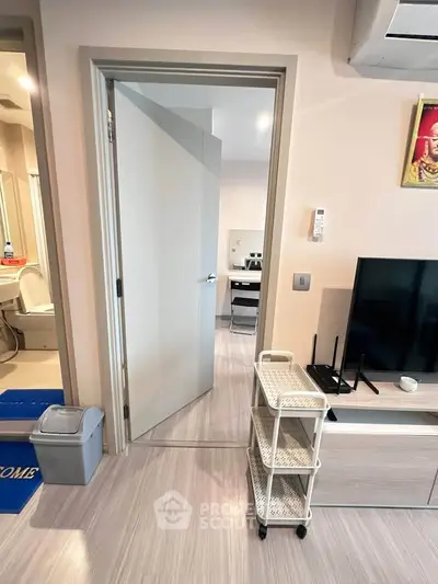Modern apartment interior with open door, TV unit, and air conditioning, showcasing sleek design and functionality.