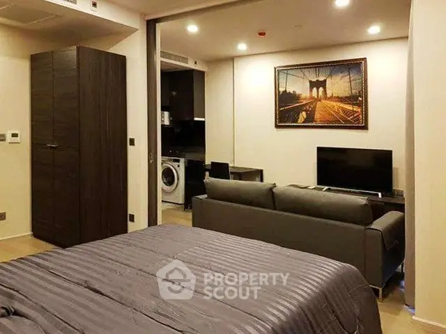 Modern studio apartment with open layout, featuring a cozy living area and stylish kitchen appliances.