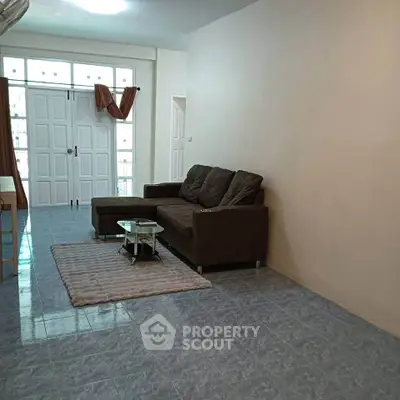 Spacious living room with modern sofa and natural light in a cozy apartment.