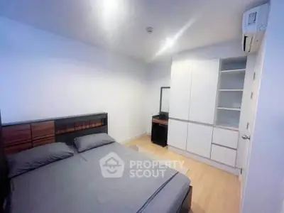 Modern bedroom with sleek design, featuring a comfortable bed, built-in wardrobe, and air conditioning.