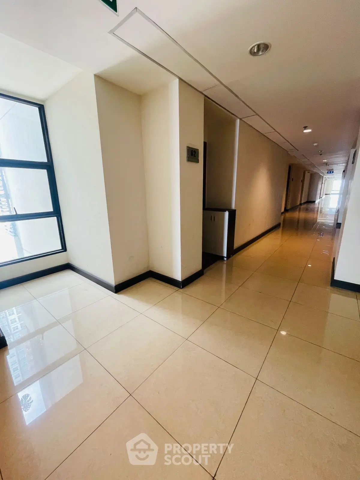 Spacious and well-lit corridor in modern building with glossy tiled floors.