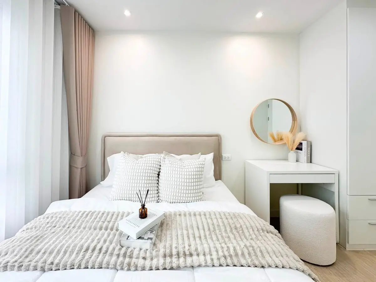 Elegant bedroom with modern decor, featuring a cozy bed, stylish pillows, and a chic vanity area.