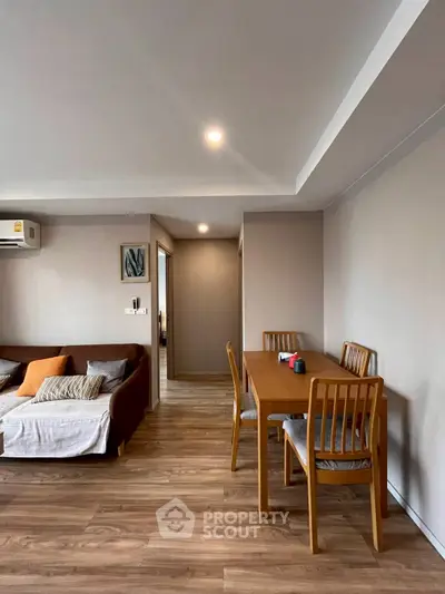 Modern living room with wooden flooring and dining area, featuring cozy sofa and stylish decor.