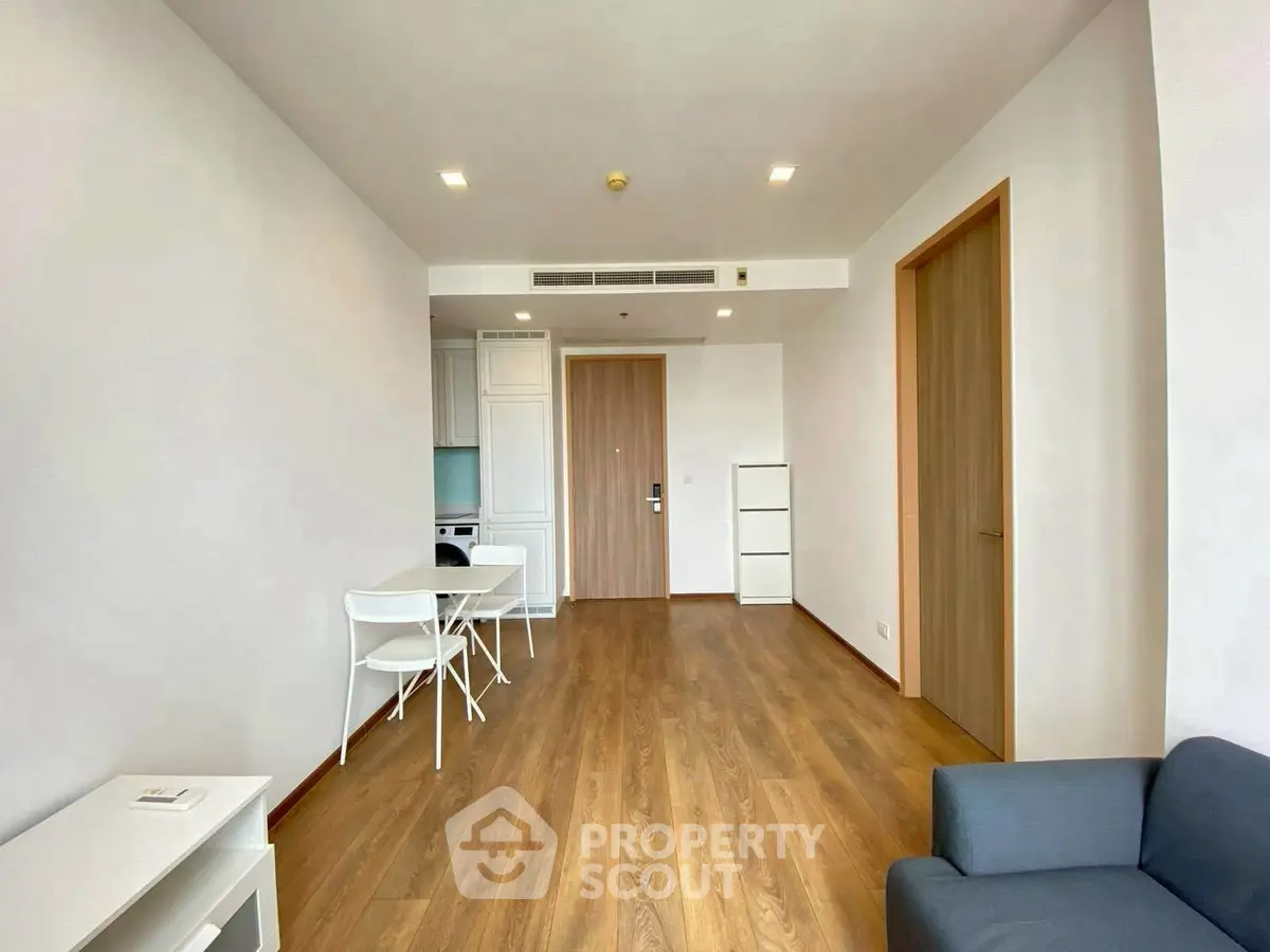 Spacious modern living room with wooden flooring and minimalist furniture in a bright apartment.