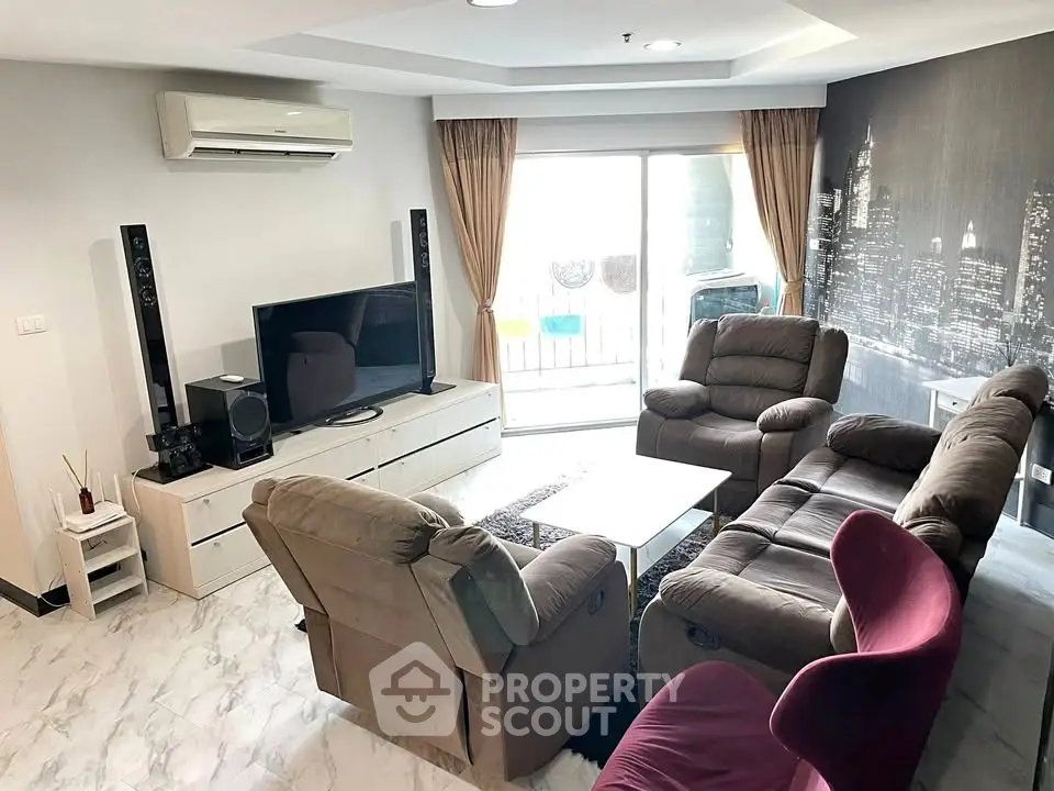 Spacious living room with modern furniture and cityscape wall art, featuring a cozy seating area and entertainment setup.