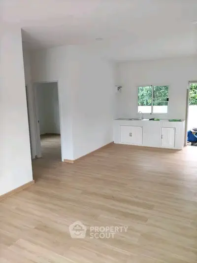 Spacious open layout living area with modern kitchen and wooden flooring.