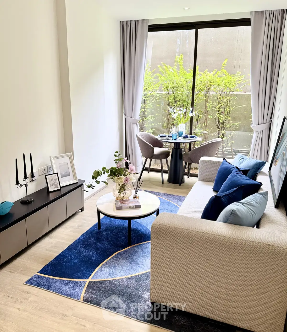 Modern living room with elegant decor and large window overlooking greenery, featuring stylish furniture and vibrant accents.