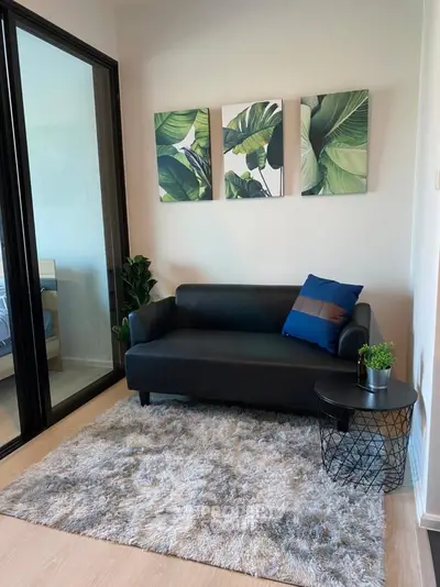 Stylish living room with modern sofa, lush decor, and cozy rug in a chic apartment.