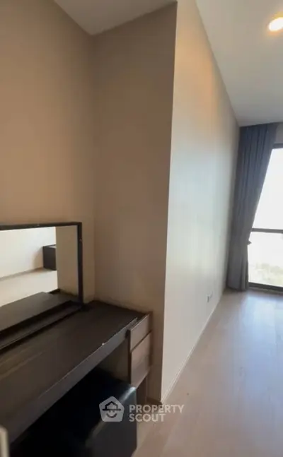 Modern bedroom with sleek vanity and large window offering natural light.